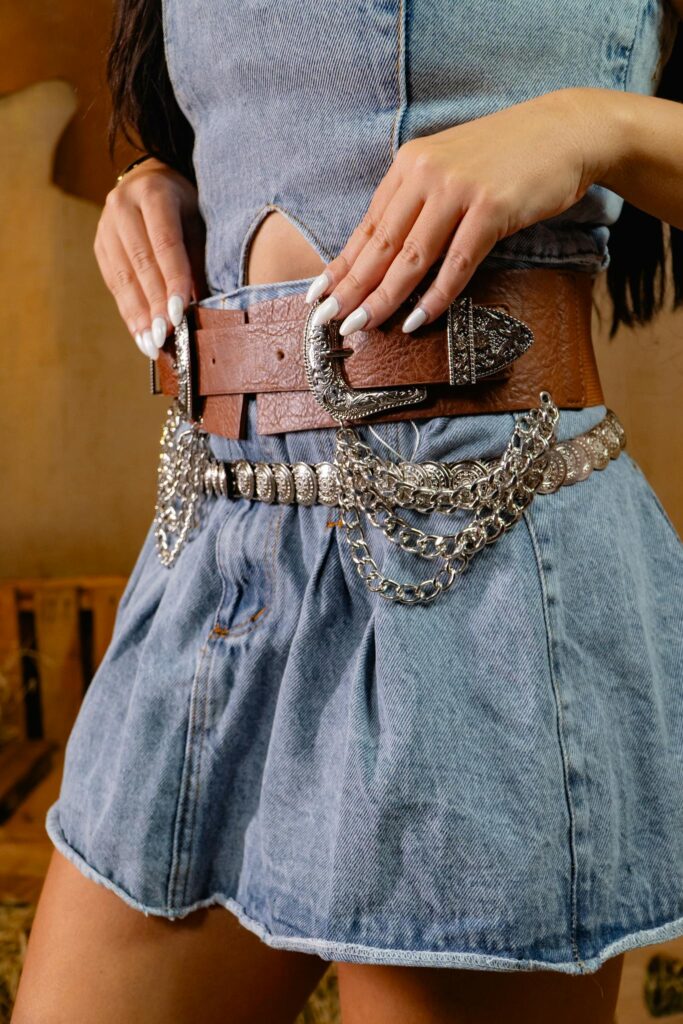 Close-up of a woman's denim outfit featuring a detailed silver and leather belt.